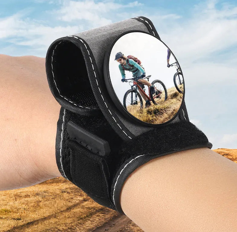 Black bicycle rear-view mirror mounted on an adjustable nylon wrist strap for cycling.