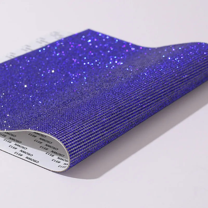 Hot-fix rhinestone transfer sheet on a roll showing sparkling electroplated stones in multiple colours on adhesive backing.