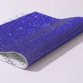 Hot-fix rhinestone transfer sheet on a roll showing sparkling electroplated stones in multiple colours on adhesive backing.
