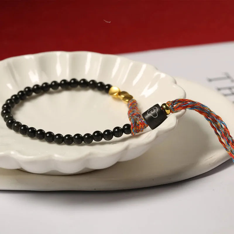 Hand-woven obsidian-coloured strap bracelet showing textured surface and slim 4mm width