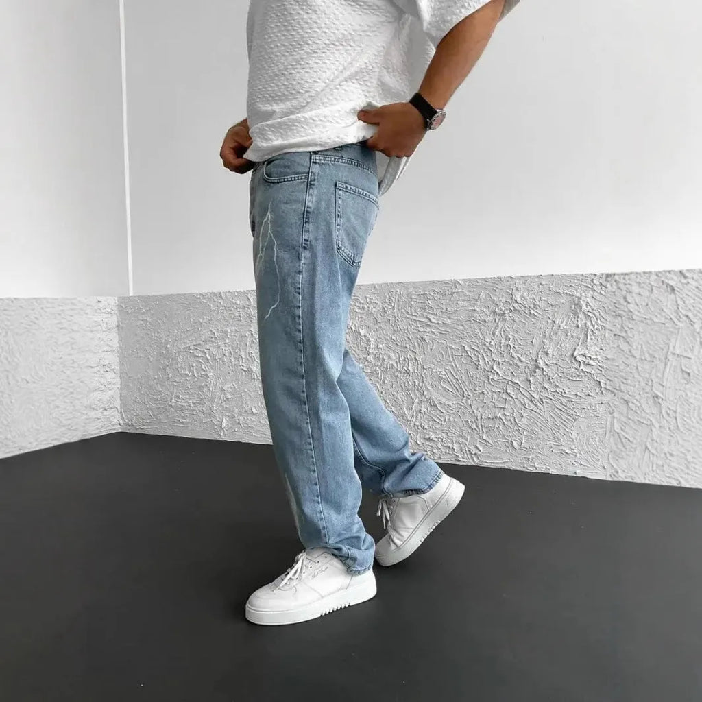 Men's blue straight-leg cotton denim trousers with a wide-leg fit and five-pocket design on a neutral background.