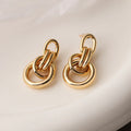 Gold geometric copper earrings with irregular asymmetric design on display