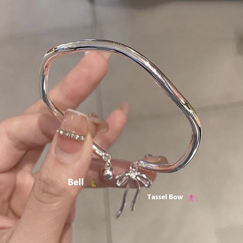 Silver bow adjustable bracelet with bow bell opening clasp on wrist