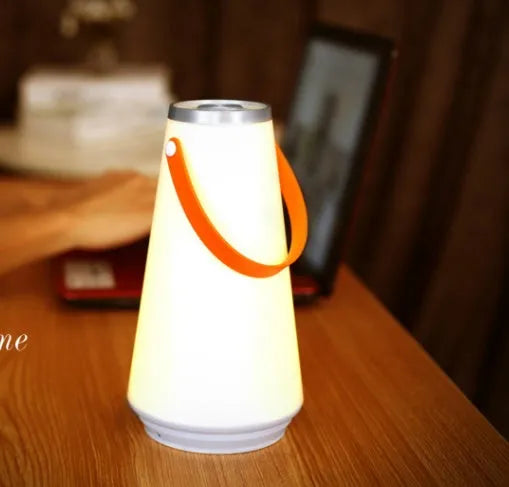 White rechargeable LED bedside lamp with adjustable brightness on a table.