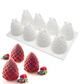 Set of six silicone baking moulds shaped like a pineapple, a pine cone, and a pear on a kitchen counter.