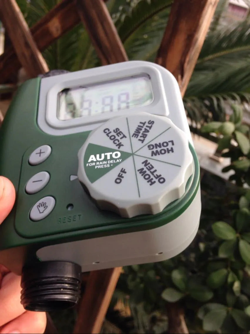 Green digital hose faucet timer with copper connector and dual outlets for garden irrigation