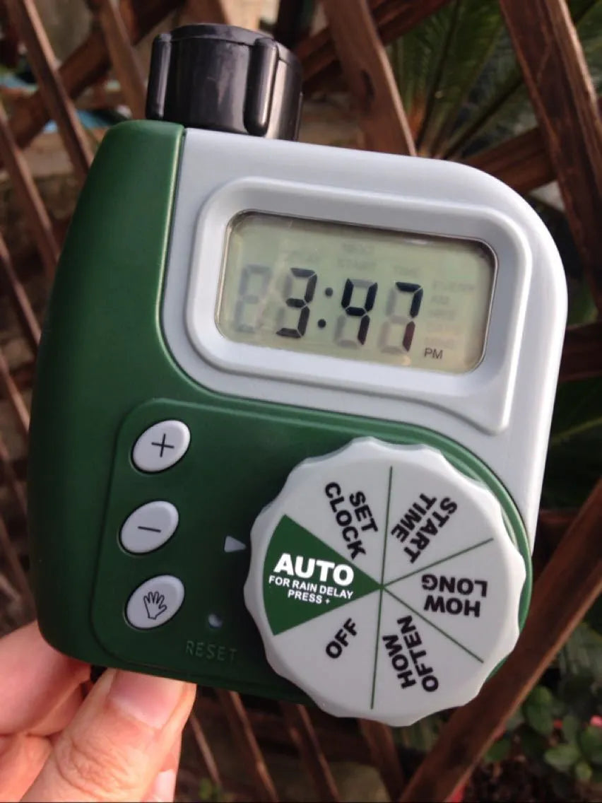 Green digital hose faucet timer with copper connector and dual outlets for garden irrigation