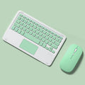 Pink wireless Bluetooth keyboard and mouse combo set on a desk next to a tablet.