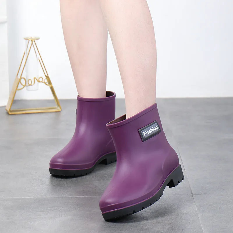 Women's mid-calf PVC rain boots in black with low heel, shown in short tube design