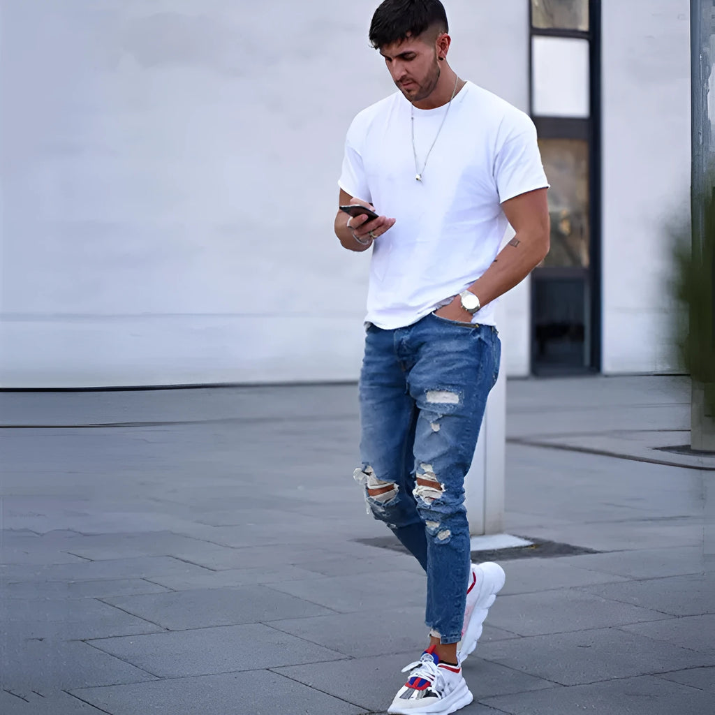 Men's blue jeans with distressed hole detailing on cotton fabric