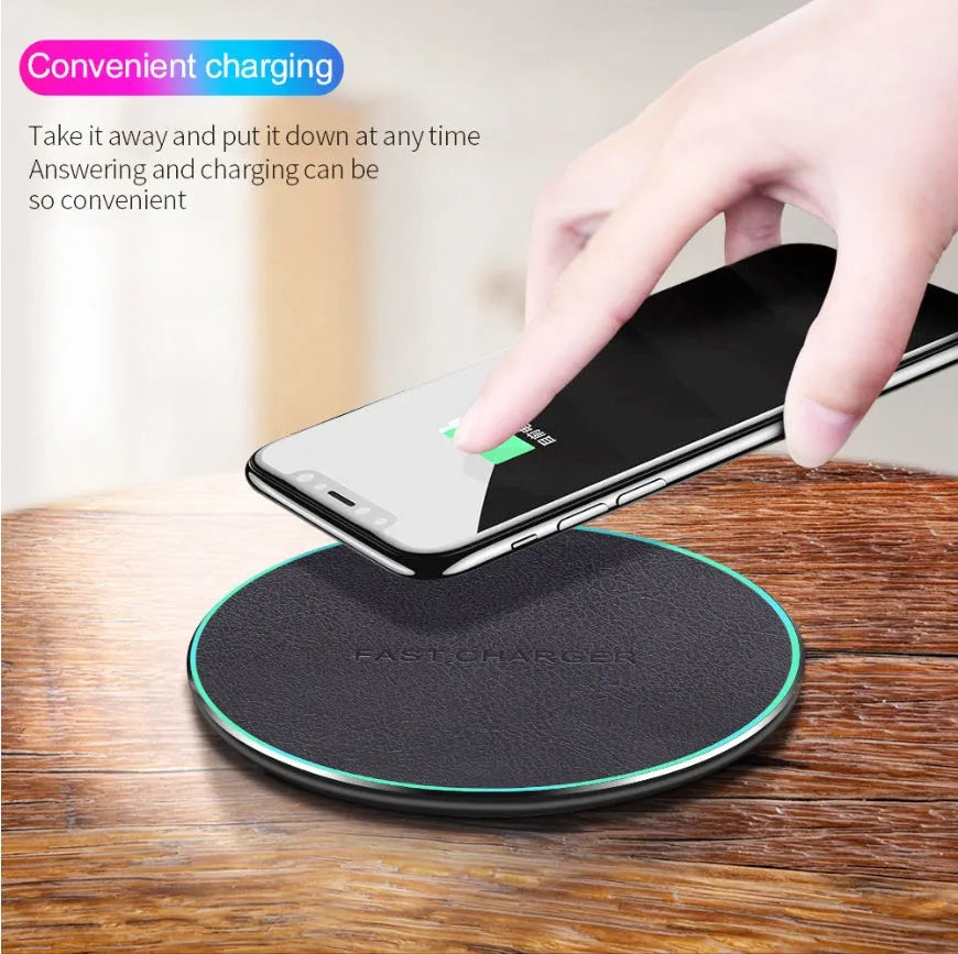 Black Qi wireless charging pad for iPhone 11 on a wooden surface.