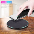 Black Qi wireless charging pad for iPhone 11 on a wooden surface.
