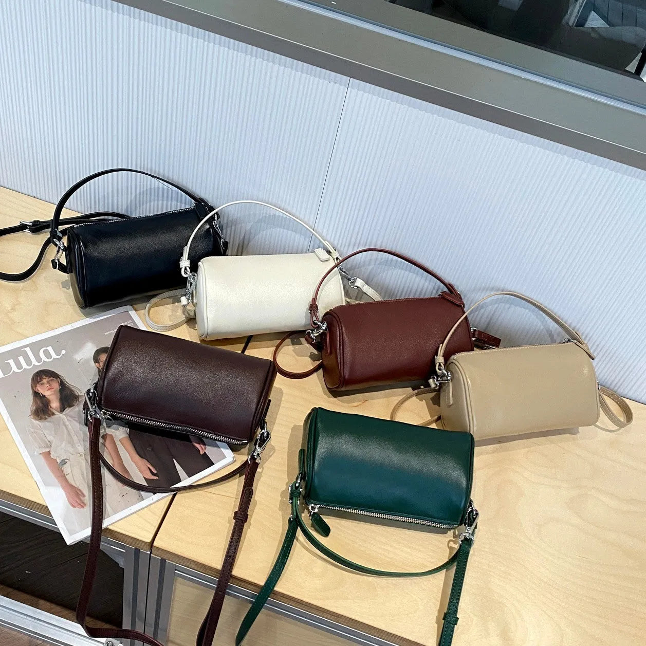 Brown cylindrical leather crossbody phone bag with visible stitching on a flat surface.