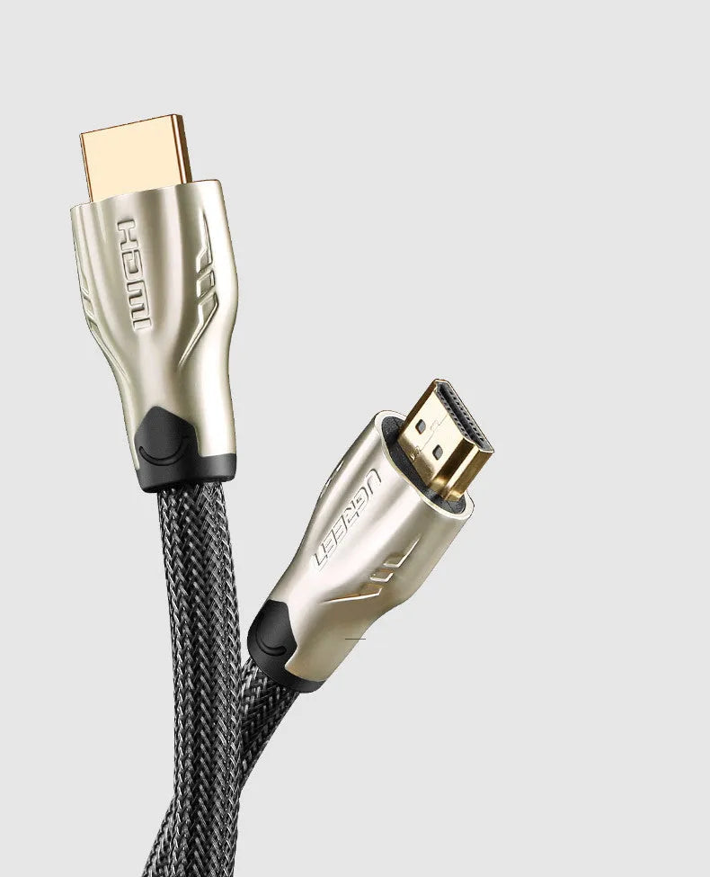 Close-up of a gold-plated HDMI connector on a black cable showing its aluminium foil and braided shielding layers.