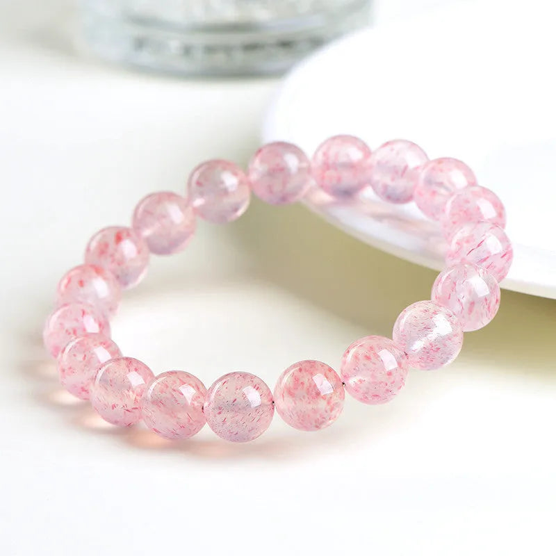Natural white strawberry quartz crystal ball bracelet with 10mm spherical beads on wrist.