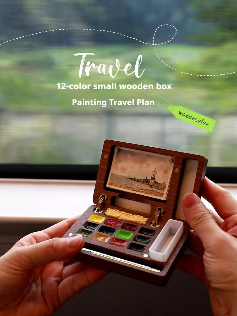 Small wooden watercolour paint box open to show artist pigment pans inside for portable painting.