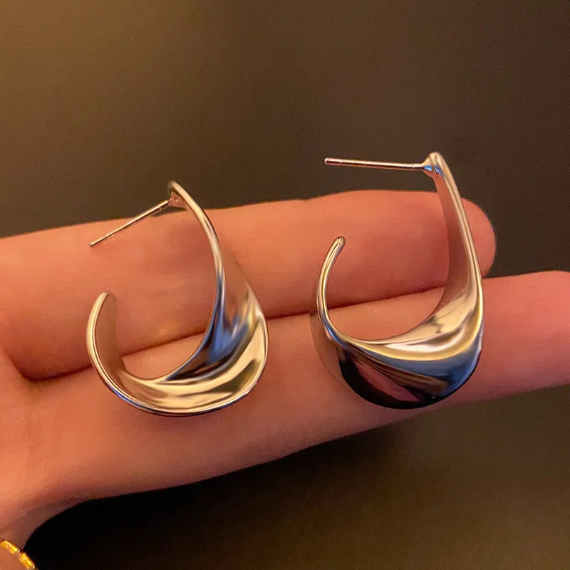 Gold and silver geometric twisted metal earrings with round design elements