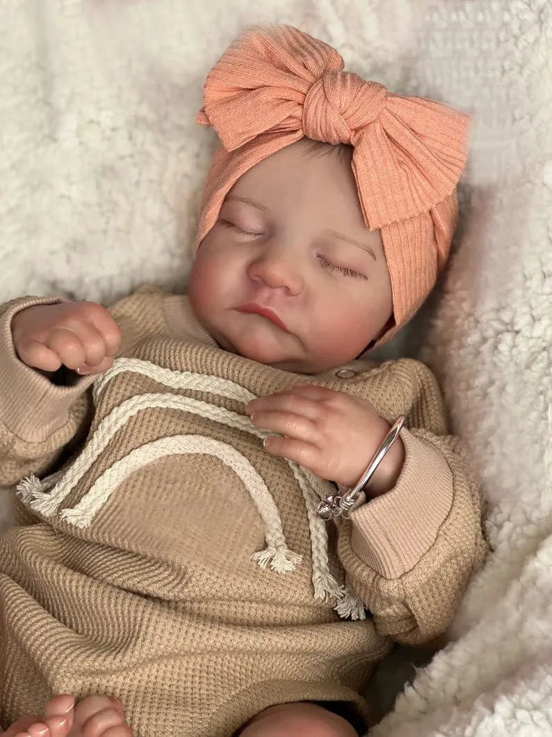 18-inch reborn doll with cloth body in soft pink romper sitting on table