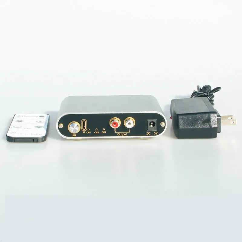 Silver aluminium audio source selector switch unit with front-panel buttons and infrared remote control.