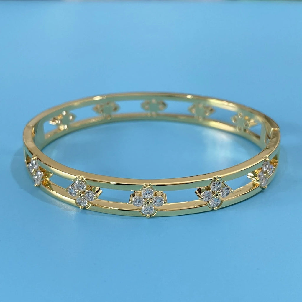 Gold or silver plated women's hollow bracelet with a four-leaf clover charm and zircon stones.