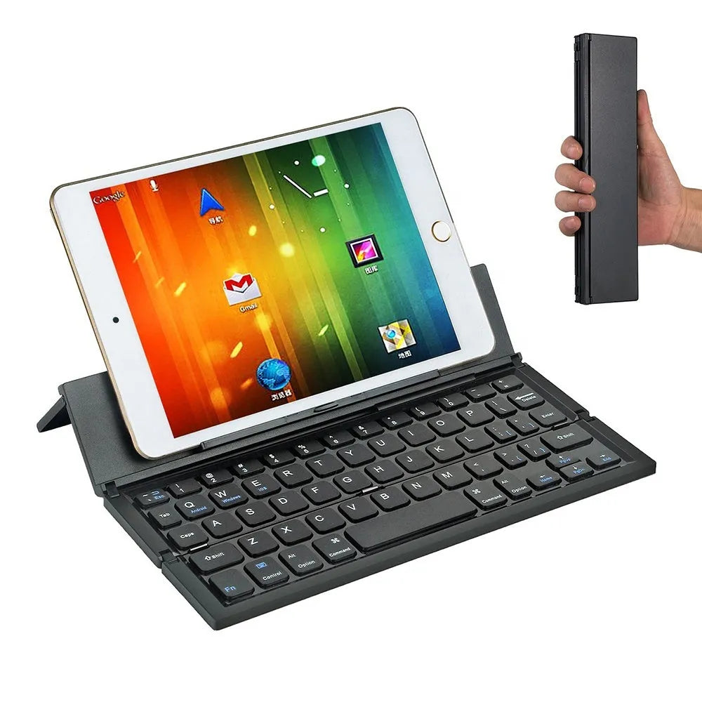 Black folding wireless Bluetooth keyboard shown open next to a tablet demonstrating its compact portable size.