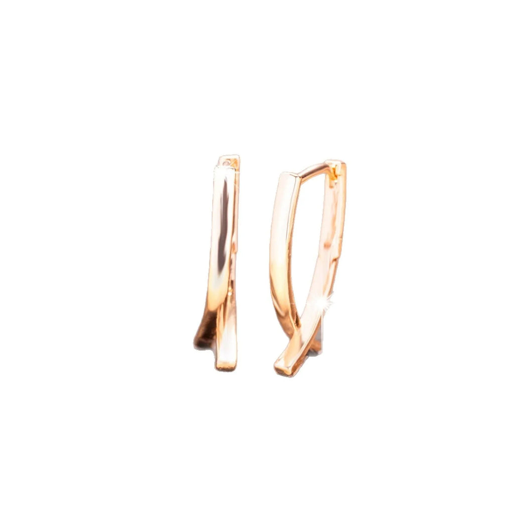 Rose gold cross shaped fashion earrings made from copper on a white background