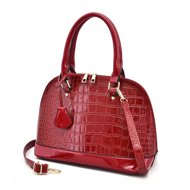 Large shiny black PU crossbody shoulder bag with shell shape design on a model.