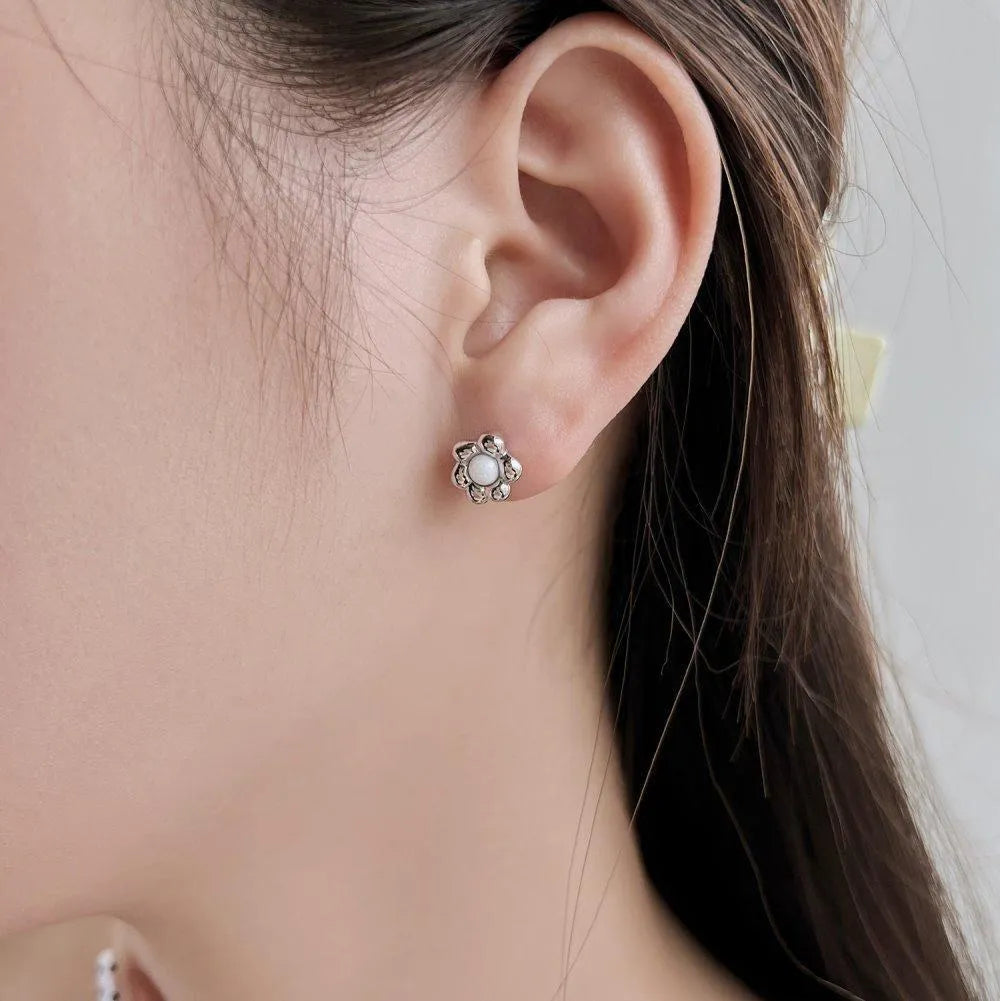 S925 sterling silver black agate flower ear studs in gold colour on a woman's ear