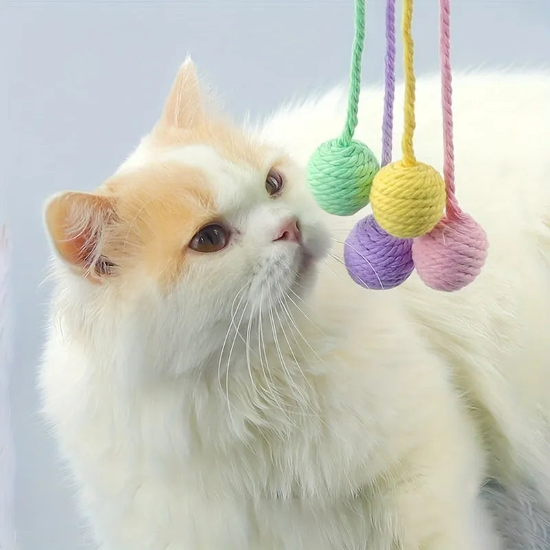 Green cat toy ball with attached rope on a wooden floor, shown next to a yellow 3cm size version.
