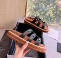 Women's retro Roman sandal slippers in black patent leather with sheepskin upper, shown from the side.