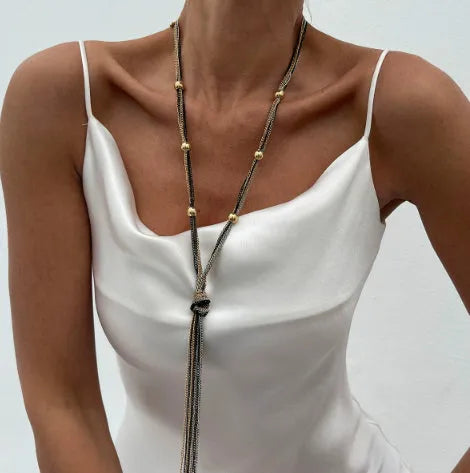 Simple Y-shaped metal tassel necklace with minimalist understated style, colour Gold, on display with matching earrings.