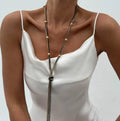 Simple Y-shaped metal tassel necklace with minimalist understated style, colour Gold, on display with matching earrings.