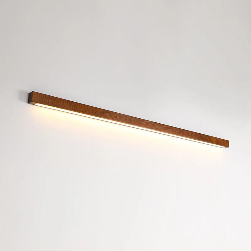 Walnut-coloured linear wood and acrylic strip wall lamp mounted on a light wall.