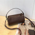 Brown cylindrical leather crossbody phone bag with visible stitching on a flat surface.