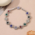 Floral shaped zinc alloy bracelet with electroplated silver finish and red coloured gemstones.