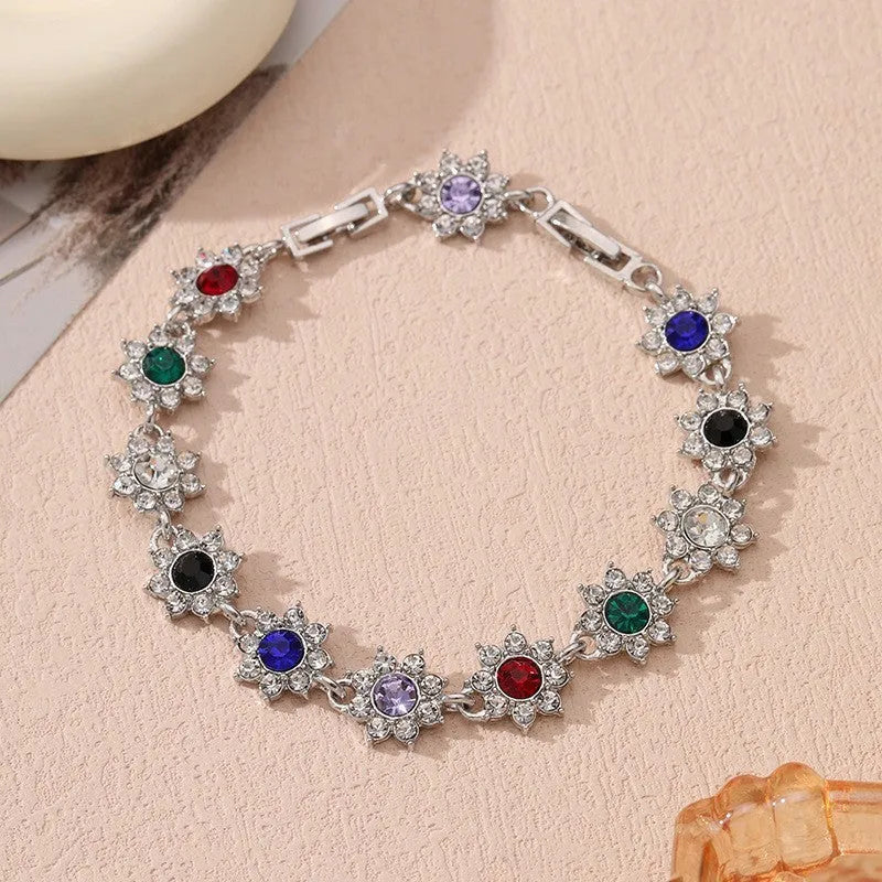 Floral shaped zinc alloy bracelet with electroplated silver finish and red coloured gemstones.