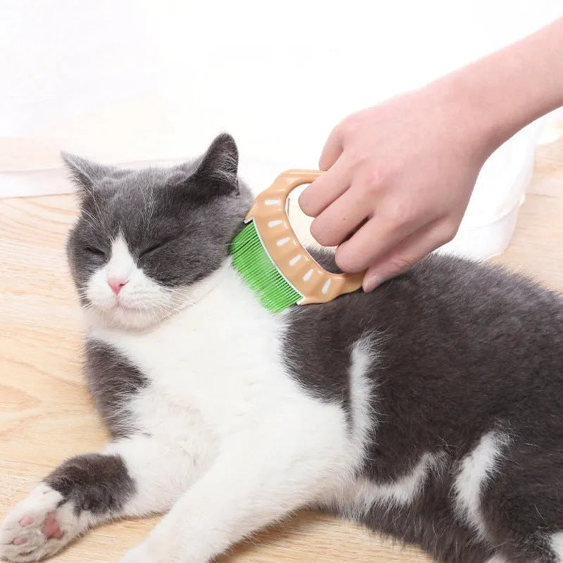 Green shell-shaped pet grooming comb with bent wire bristles and a plastic handle.