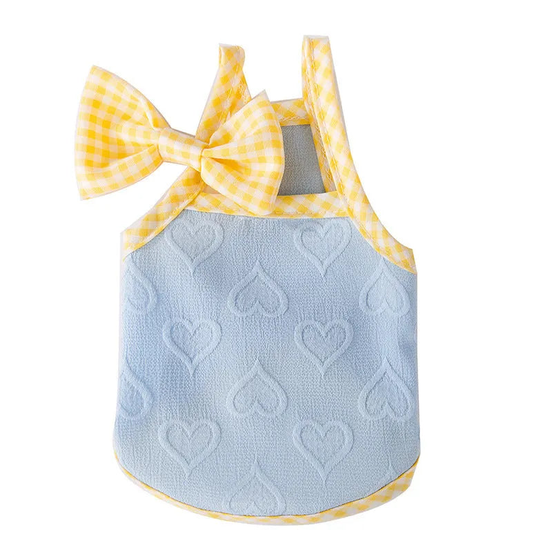 Small dog wearing blue vest with heart texture bow and matching hairband