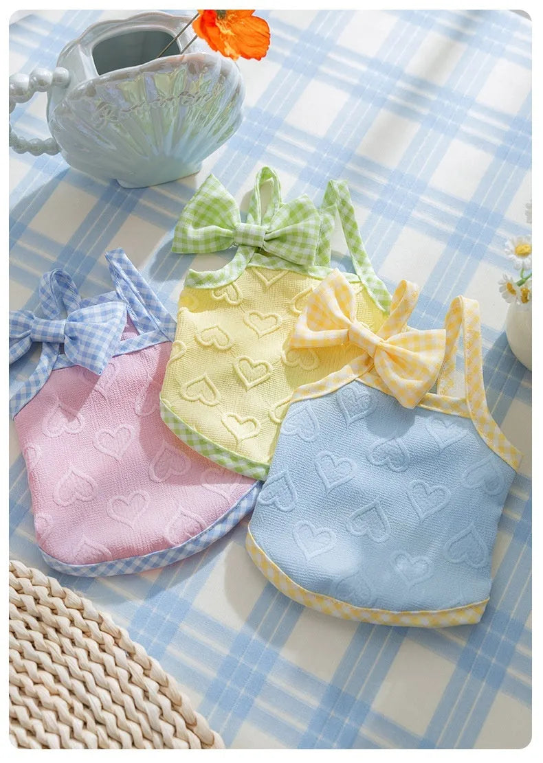 Small dog wearing blue vest with heart texture bow and matching hairband