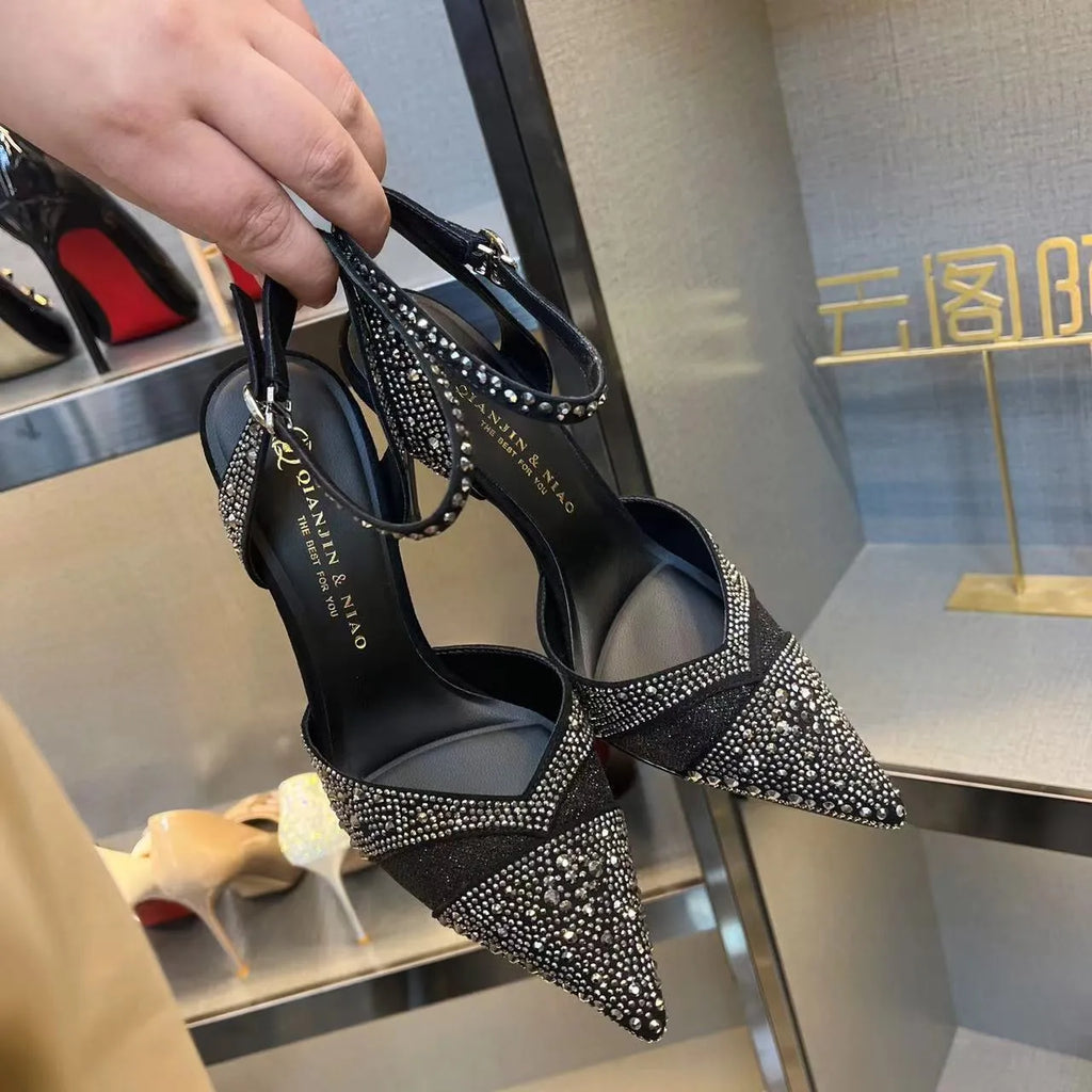Women's black high heels with hollow stiletto heel, pointed toe, and a bright red sole.
