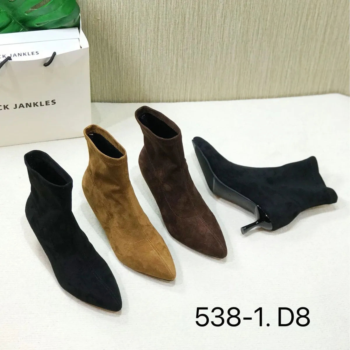 Black pointed toe stiletto ankle boots with a mid-calf sock on a plain background.