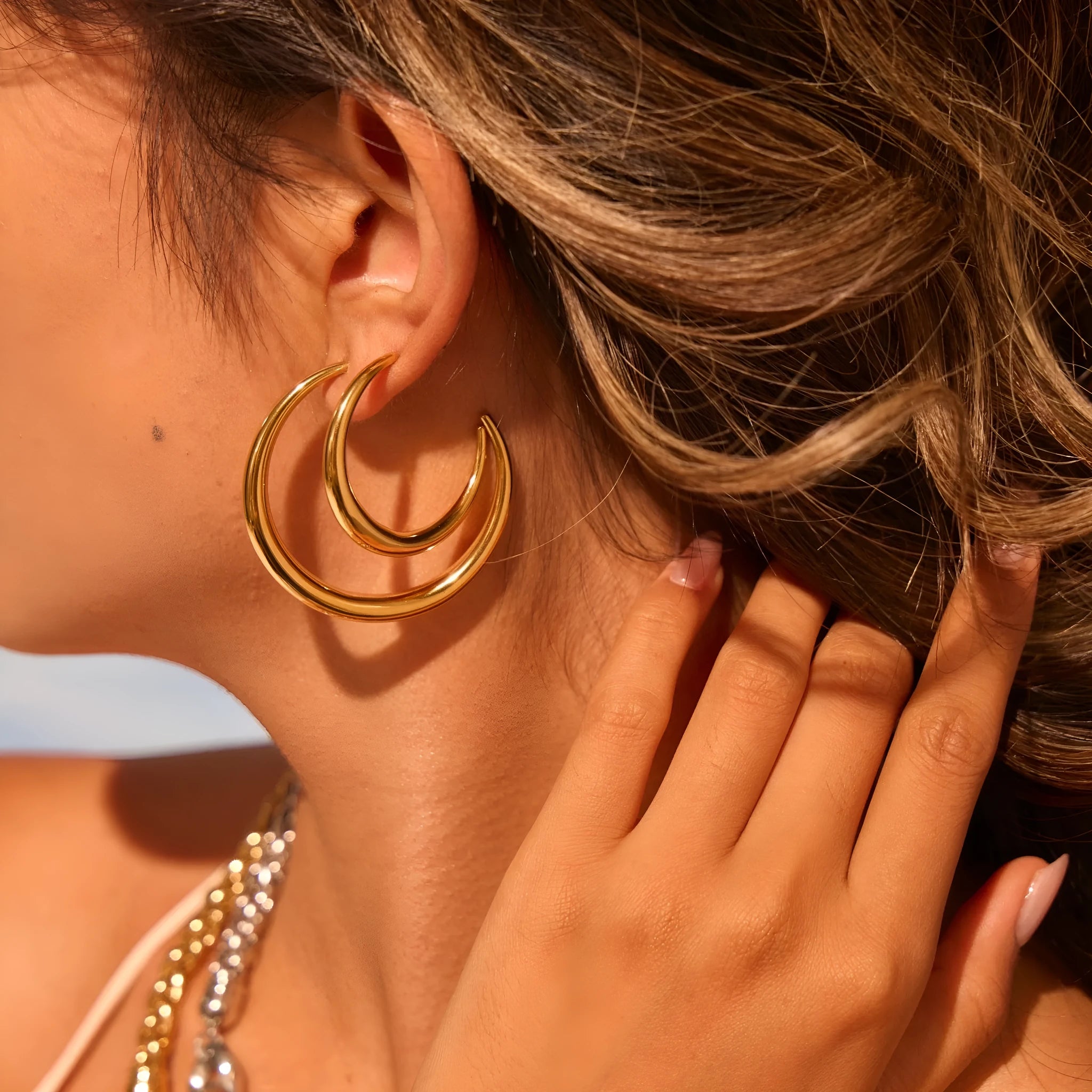 Simple round titanium steel hoop earrings for women in gold and steel finishes, shown in large and small sizes.