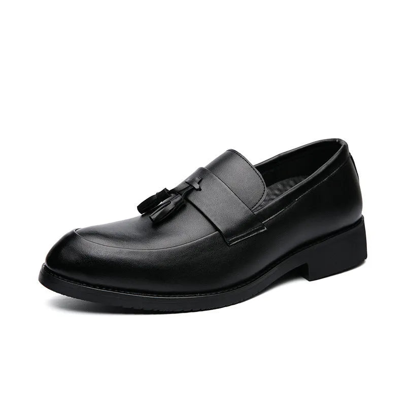 Men's black slip-on business casual shoes with tassel detail and plain toe on wooden floor