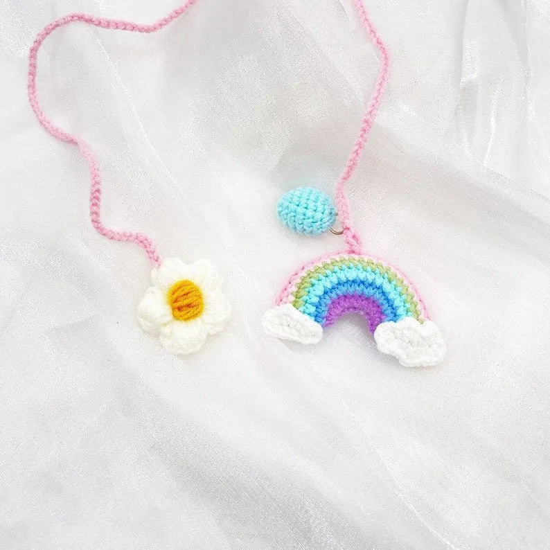 Handmade crocheted wool car pendant shaped like a cartoon avocado with a rainbow flower decoration.