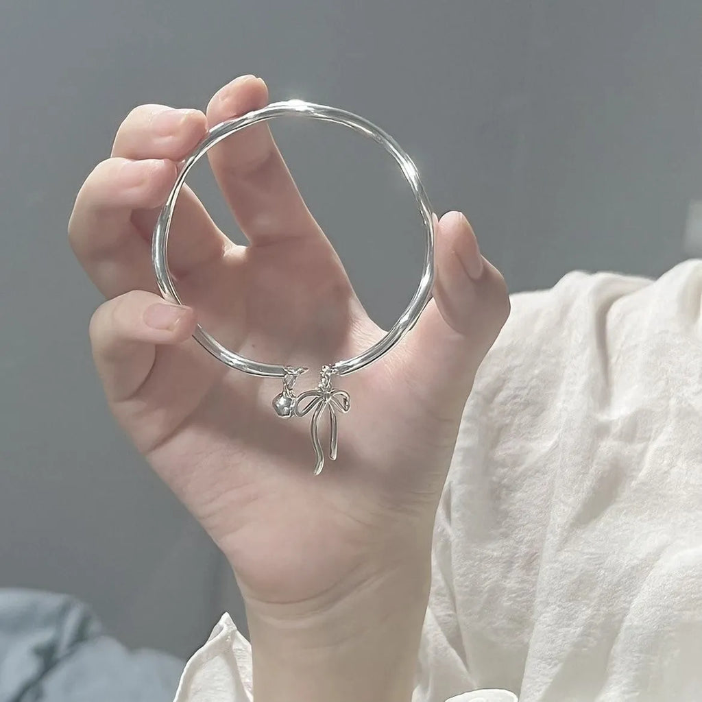Silver bow adjustable bracelet with bow bell opening clasp on wrist