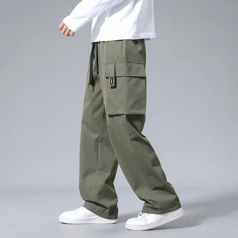 Boy wearing straight leg cargo pants with drawstring waist and large side pockets in army green.