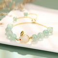 Rabbit charm bracelet with green aventurine or strawberry quartz stones and gold accents on a wrist.