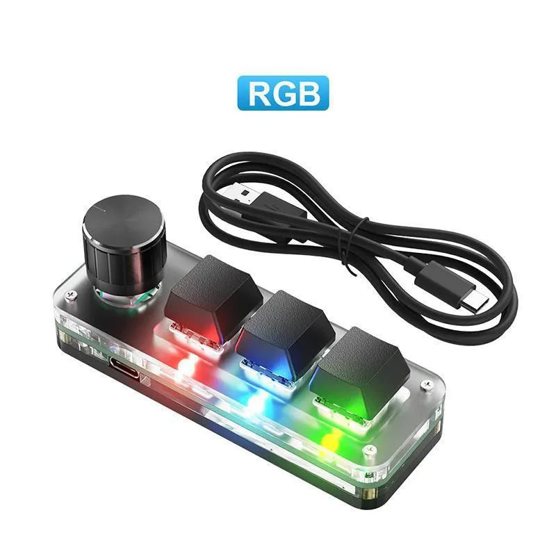 Black programmable mini keyboard with RGB backlighting on a desk next to a laptop