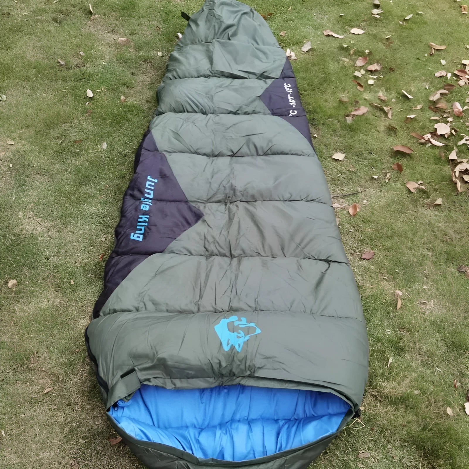 Outdoor cotton sleeping bag in army green with its compression sack, shown partially rolled.