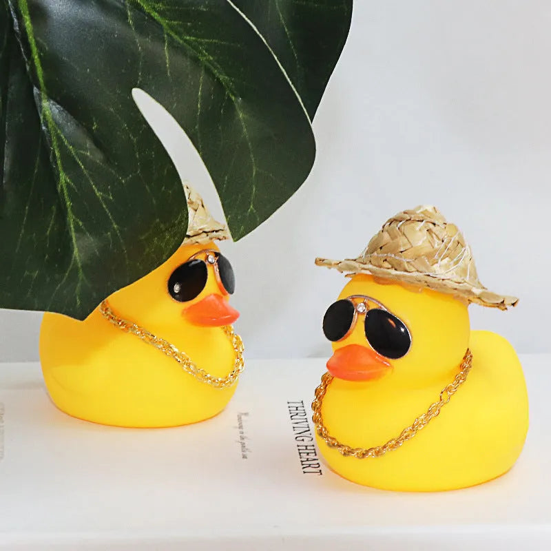 Matte yellow cartoon duck wearing a straw hat car ornament on a dashboard.